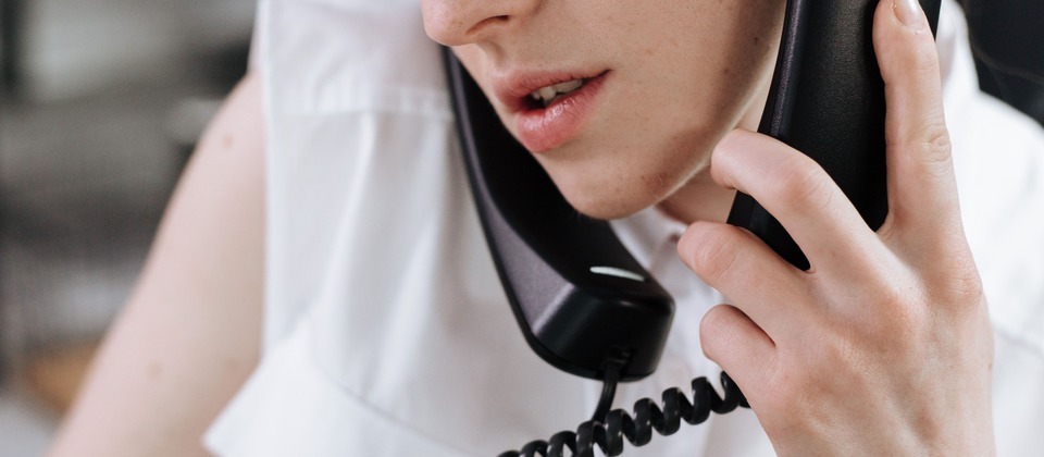 A customer service representative talking on a traditional office landline phone with a coiled cord.