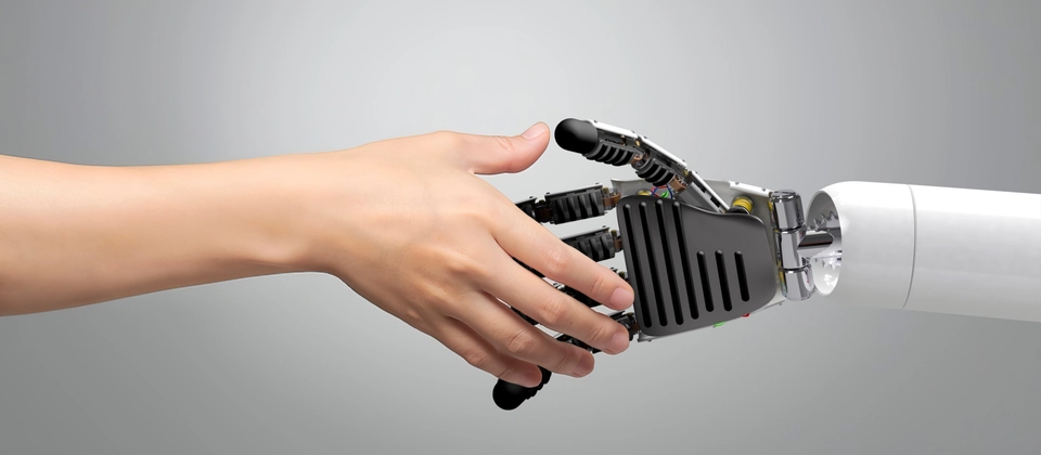A human hand shaking a robotic hand, symbolizing human and artificial intelligence collaboration.